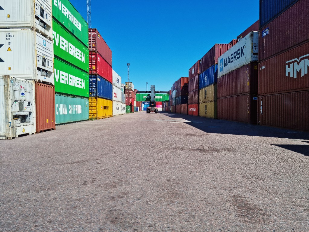 Container stacks in a port yard with reach stacker moving cargo